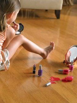 niña jugando con esmalte de uñas en piso barnizado