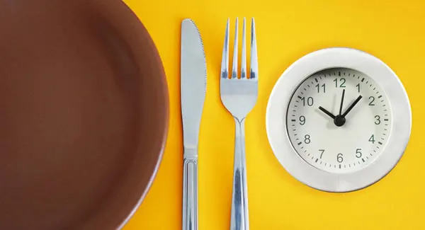 plato y utensilios al lado de un reloj